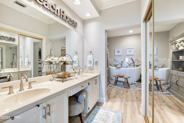 bathroom with vanity, crown molding, wood-type flooring, and a tub to relax in