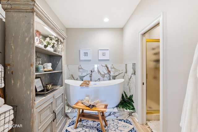 bathroom featuring tile walls and independent shower and bath