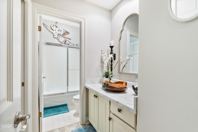 full bathroom featuring vanity, toilet, and bath / shower combo with glass door