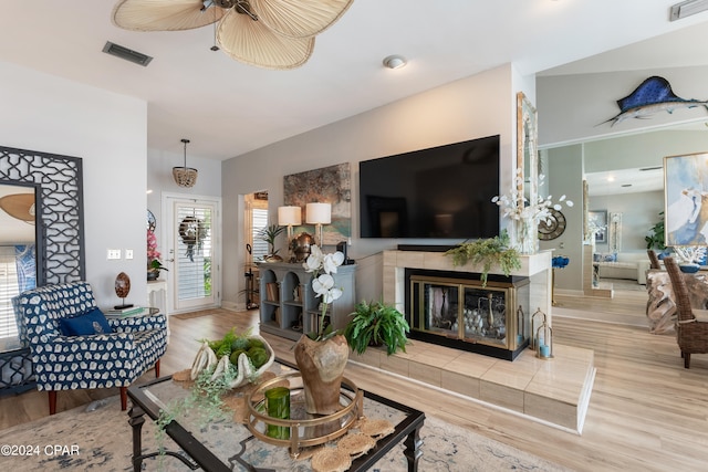 living room with a tile fireplace, light hardwood / wood-style flooring, and ceiling fan