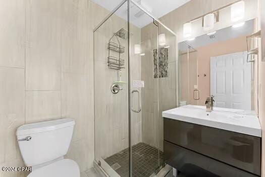 208 3rd St Unit 1/2, Panama City Beach, FL 32413 - full bathroom featuring vanity, toilet, a stall shower, and tile walls