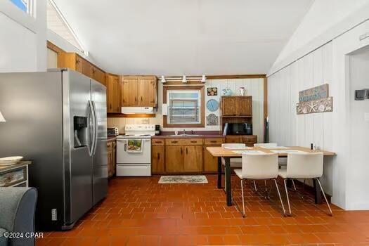 208 3rd St Unit 1/2, Panama City Beach, FL 32413 - kitchen featuring white electric range oven, stainless steel fridge, brown cabinets, under cabinet range hood, and lofted ceiling