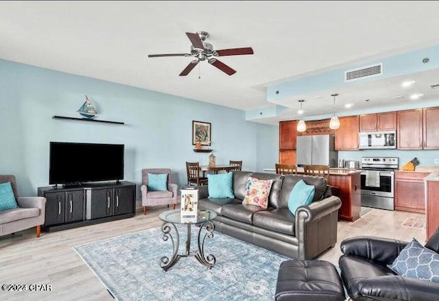 living area with light wood-style floors, visible vents, and ceiling fan