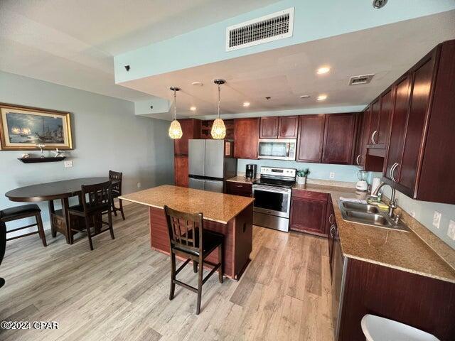 kitchen featuring stainless steel appliances, a sink, visible vents, and light wood-style floors