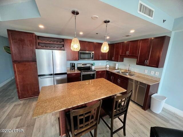 kitchen with light wood finished floors, visible vents, stainless steel appliances, and a sink