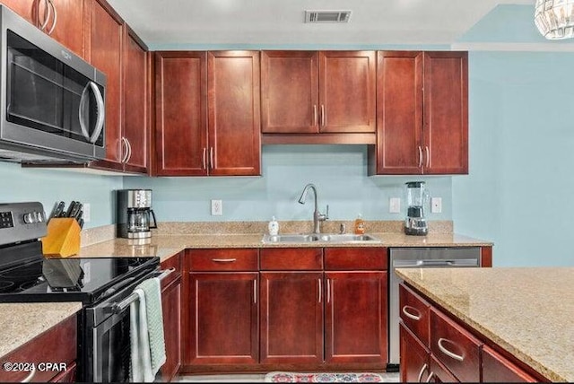 kitchen with visible vents, light stone counters, appliances with stainless steel finishes, dark brown cabinets, and a sink