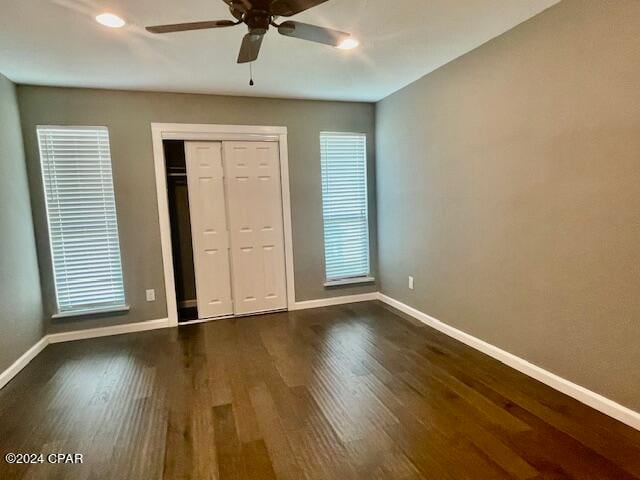 unfurnished bedroom featuring ceiling fan, a closet, and dark wood-type flooring