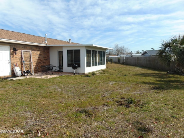 back of house with a yard, a patio area, and a sunroom