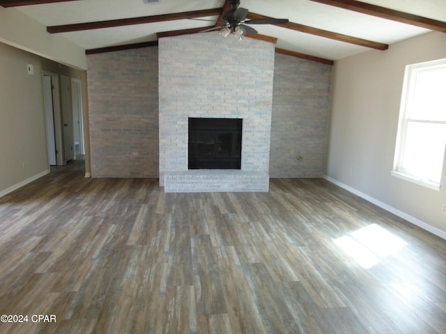 unfurnished living room featuring lofted ceiling with beams, ceiling fan, dark wood-type flooring, and a brick fireplace