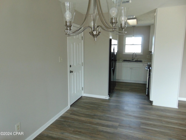 unfurnished dining area with dark hardwood / wood-style floors, an inviting chandelier, and sink