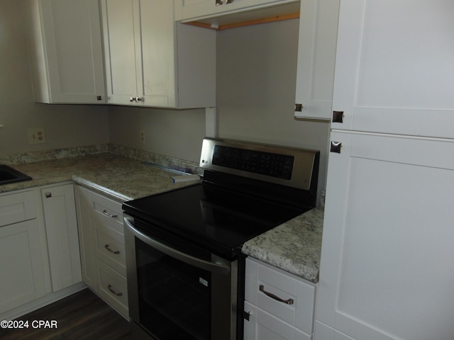 kitchen with stainless steel range with electric cooktop, white cabinets, sink, dark hardwood / wood-style floors, and light stone countertops