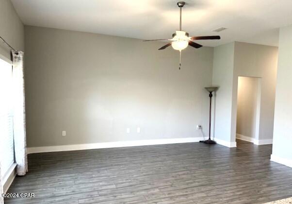 unfurnished room with ceiling fan and dark wood-type flooring