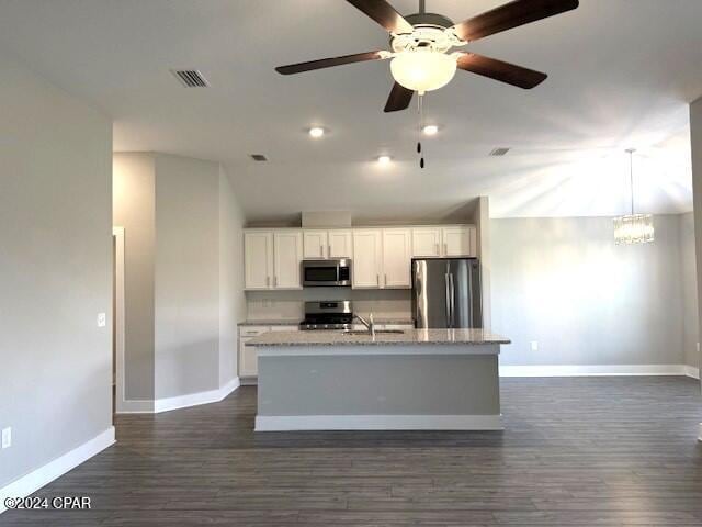 kitchen with appliances with stainless steel finishes, vaulted ceiling, a kitchen island with sink, dark hardwood / wood-style floors, and white cabinetry