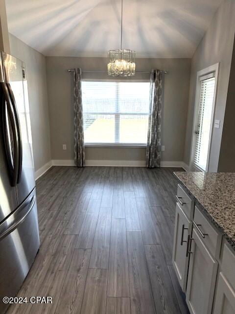 kitchen featuring stainless steel refrigerator, a healthy amount of sunlight, dark wood-type flooring, and lofted ceiling