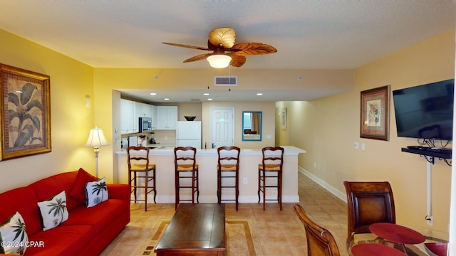 tiled living room featuring ceiling fan and a textured ceiling