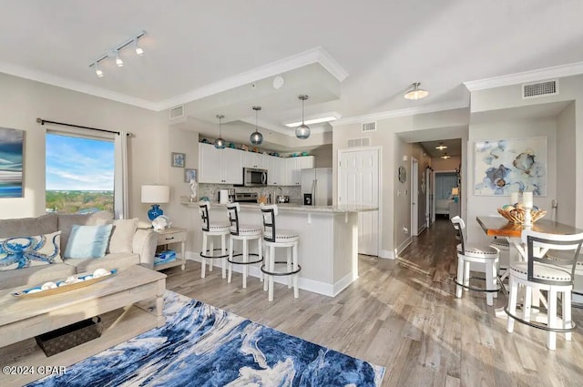 living room featuring track lighting, ornamental molding, and light hardwood / wood-style floors