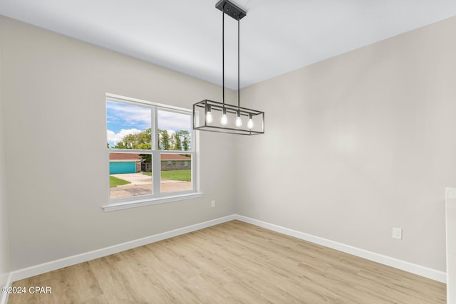 unfurnished dining area with light hardwood / wood-style floors and an inviting chandelier