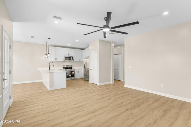 interior space featuring appliances with stainless steel finishes, light hardwood / wood-style flooring, kitchen peninsula, and ceiling fan