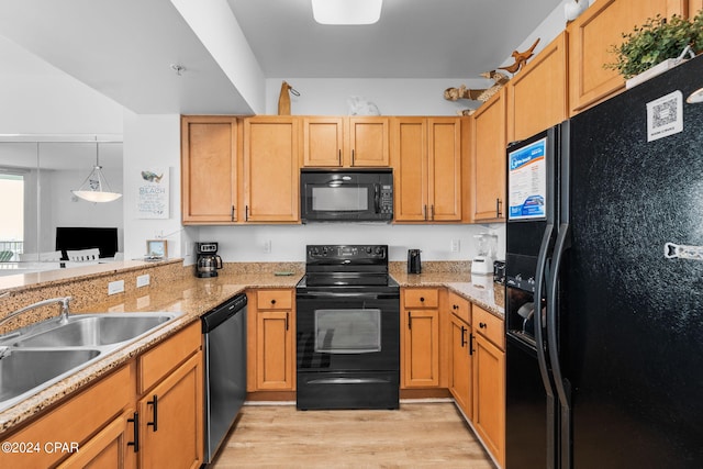 kitchen featuring light stone countertops, light wood-type flooring, black appliances, kitchen peninsula, and sink