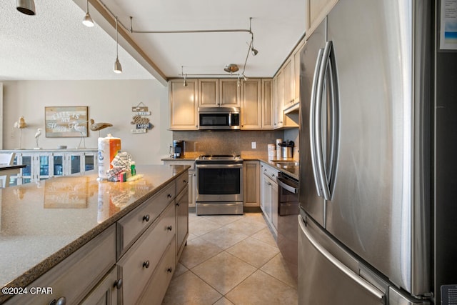 kitchen with track lighting, stainless steel appliances, light tile patterned floors, decorative backsplash, and light stone countertops