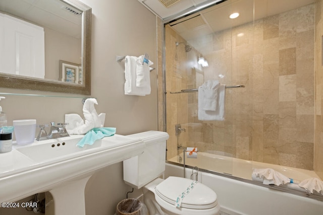 full bathroom featuring bath / shower combo with glass door, toilet, and sink