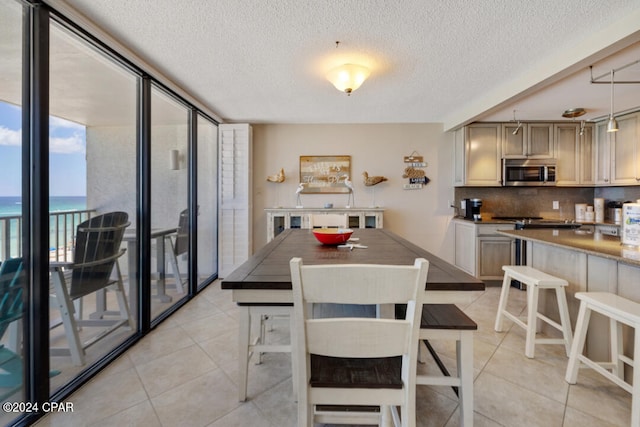 tiled dining room with a water view, a textured ceiling, and floor to ceiling windows