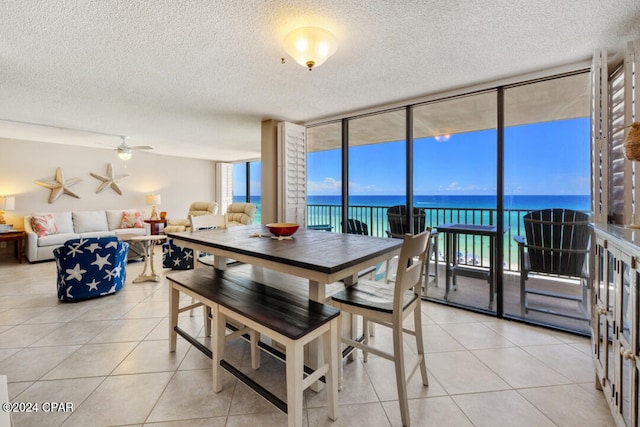 tiled dining room with a textured ceiling, a water view, and a healthy amount of sunlight