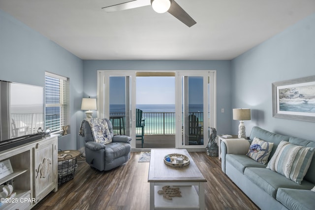 living room with dark hardwood / wood-style flooring, ceiling fan, and a water view