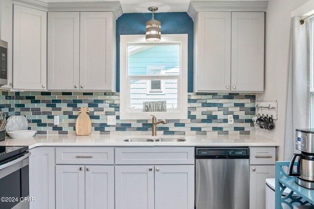 kitchen featuring white cabinets, stainless steel appliances, tasteful backsplash, sink, and pendant lighting