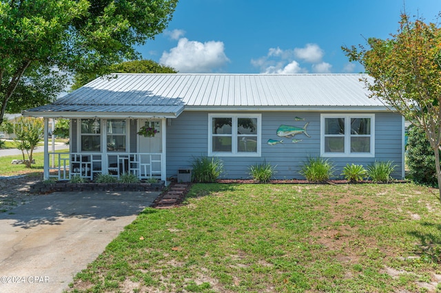 ranch-style home featuring a front lawn, covered porch, and metal roof