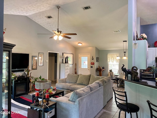 tiled living room with ceiling fan, a textured ceiling, and lofted ceiling