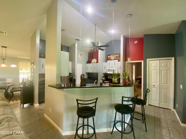 kitchen featuring ceiling fan, light tile patterned flooring, kitchen peninsula, and white cabinets