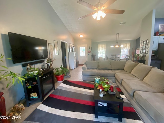 tiled living room with ceiling fan with notable chandelier and high vaulted ceiling