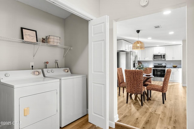 washroom with light wood-type flooring and washer and dryer