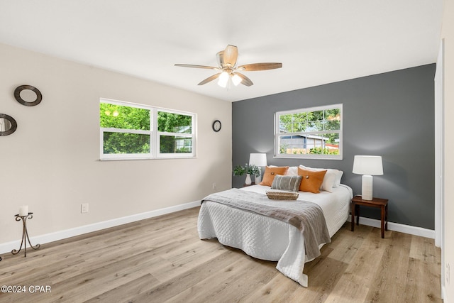 bedroom featuring ceiling fan, light hardwood / wood-style floors, and multiple windows