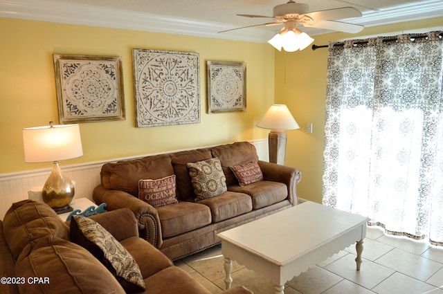 tiled living room with ceiling fan, ornamental molding, and wood walls