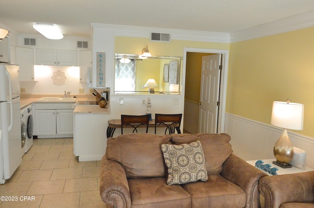 tiled living room featuring sink, ornamental molding, and washer / dryer