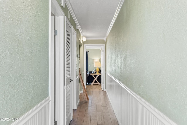 hall with a textured ceiling and ornamental molding