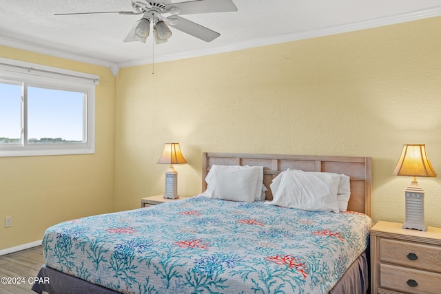 bedroom featuring hardwood / wood-style floors, a textured ceiling, ceiling fan, and ornamental molding