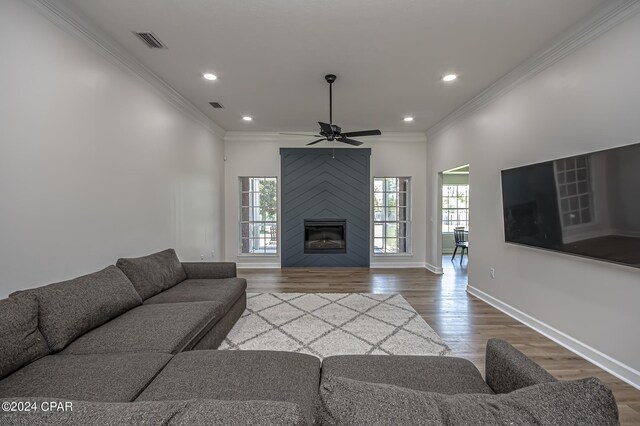 living room with a large fireplace, ceiling fan, hardwood / wood-style flooring, and ornamental molding