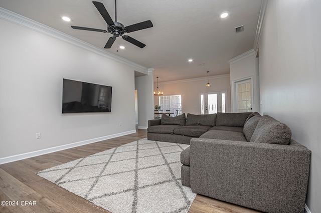 living room with ornamental molding, ceiling fan with notable chandelier, and wood-type flooring