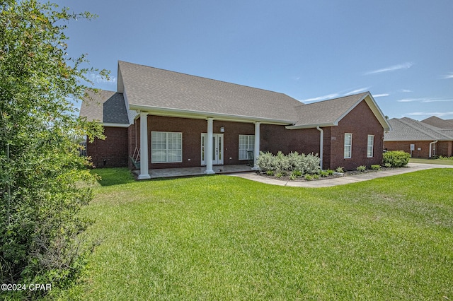 view of front of property featuring a front lawn, brick siding, and roof with shingles