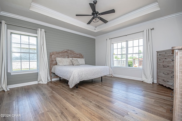 bedroom with a tray ceiling, hardwood / wood-style flooring, ornamental molding, and ceiling fan