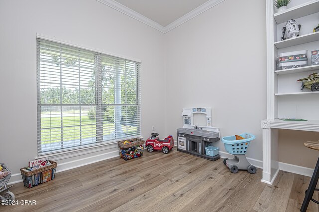 game room with a healthy amount of sunlight, ornamental molding, and light hardwood / wood-style floors