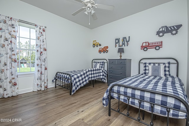 bedroom with ceiling fan, multiple windows, and wood finished floors