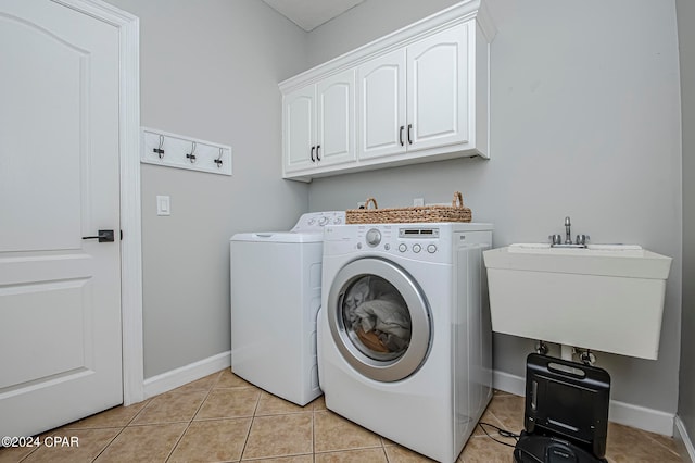 clothes washing area featuring light tile patterned floors, sink, cabinets, and washer and dryer