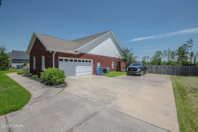 view of side of property featuring a garage, a yard, and central air condition unit