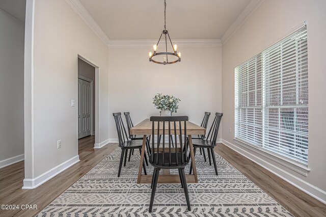 dining space featuring crown molding, an inviting chandelier, and hardwood / wood-style flooring