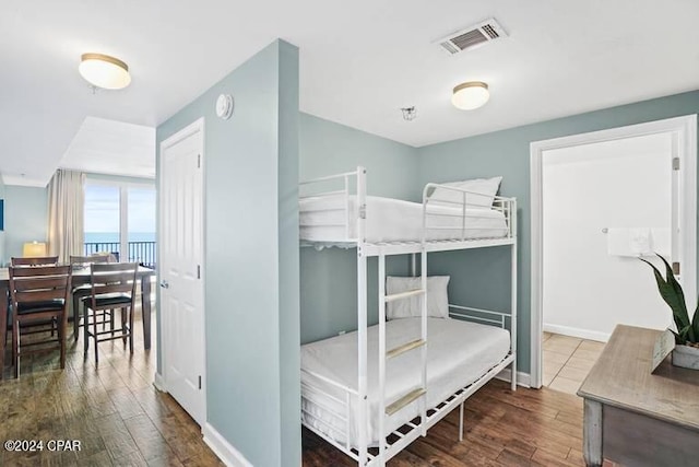 bedroom featuring hardwood / wood-style floors and a water view