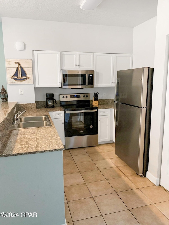 kitchen featuring a textured ceiling, light tile patterned flooring, sink, white cabinets, and stainless steel appliances